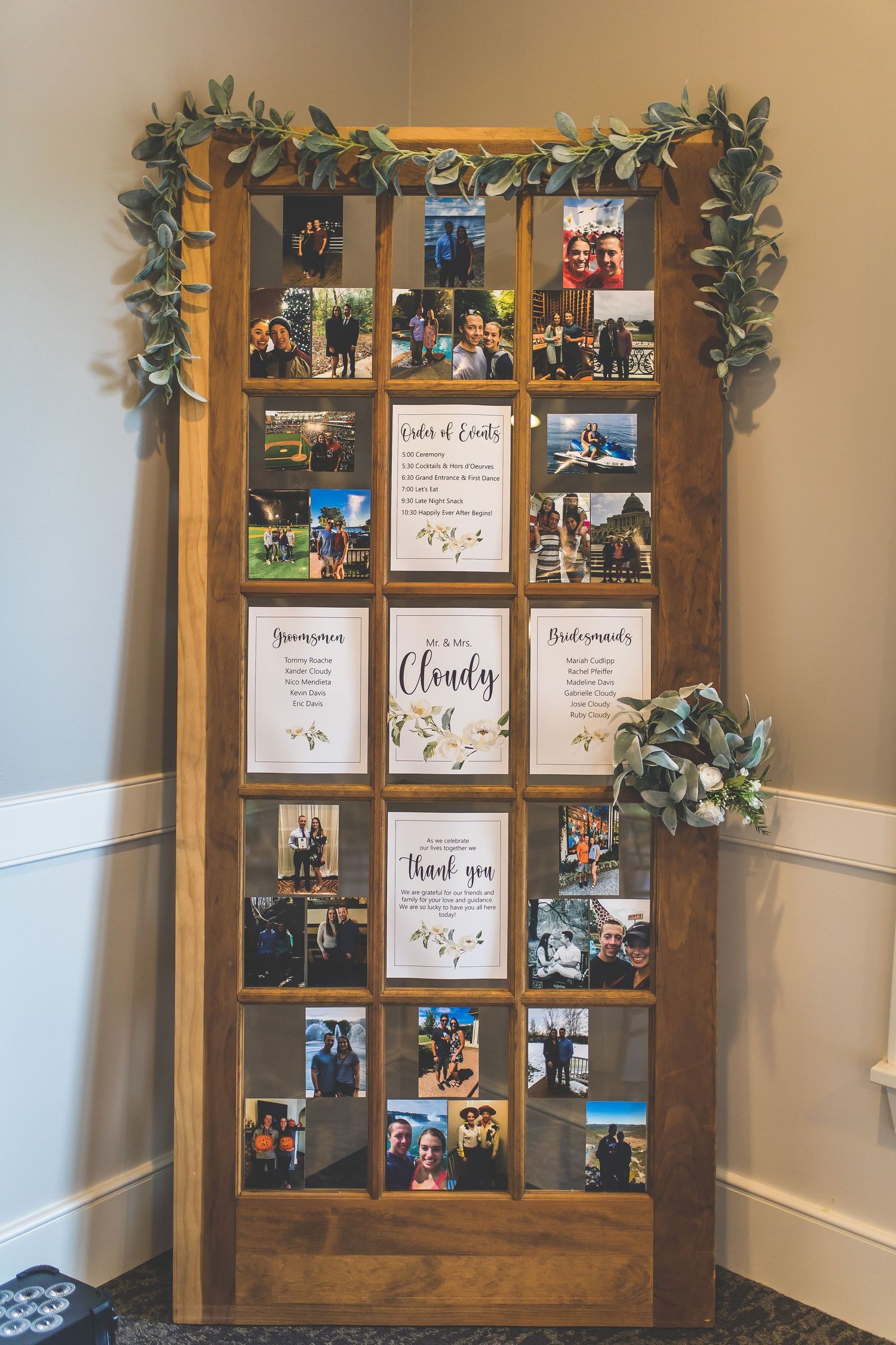Rustic wooden window frame display featuring wedding photos and decorative greenery garland.