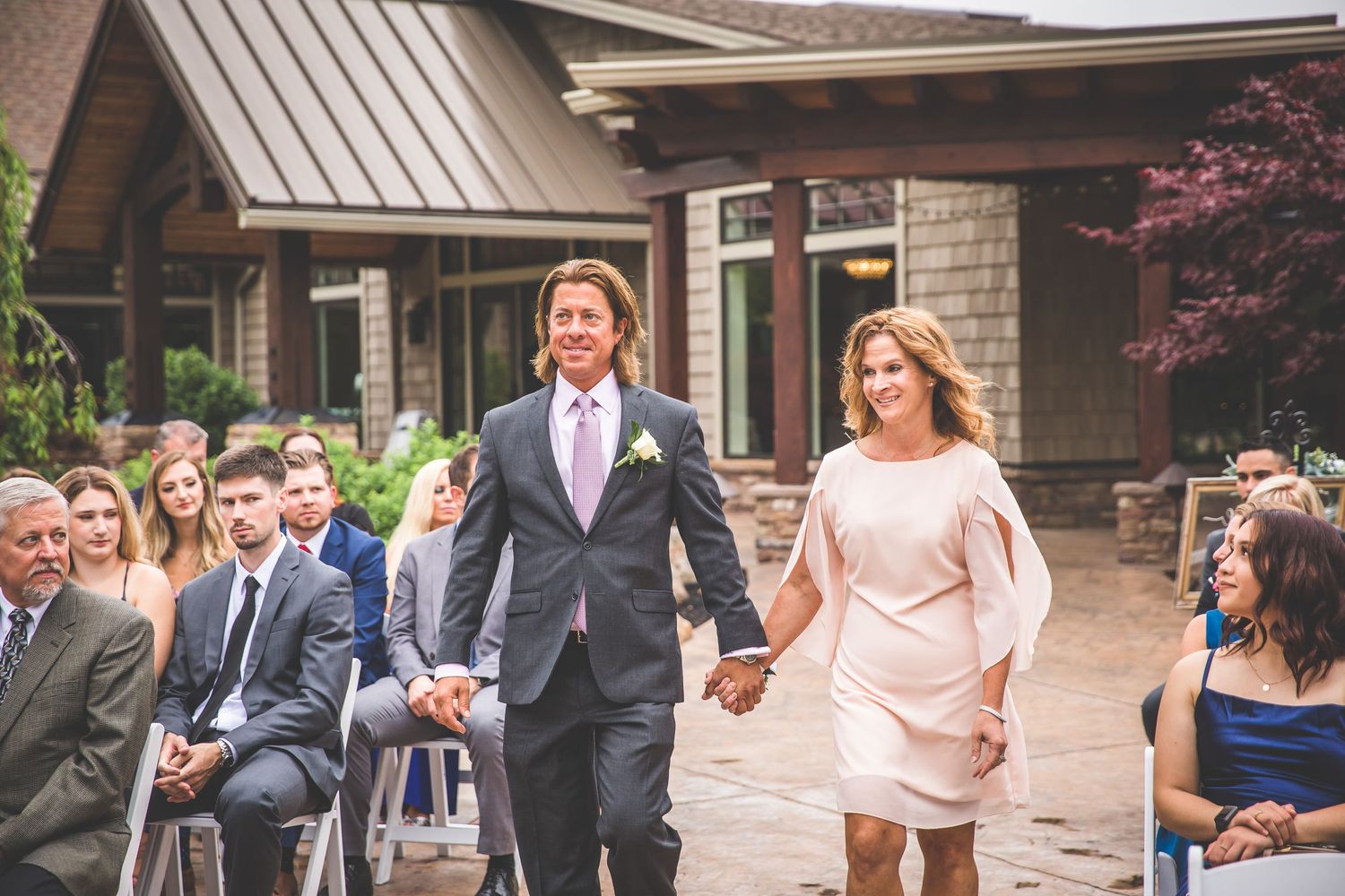 Wedding party members in blue and pink attire stand together during an outdoor celebration.