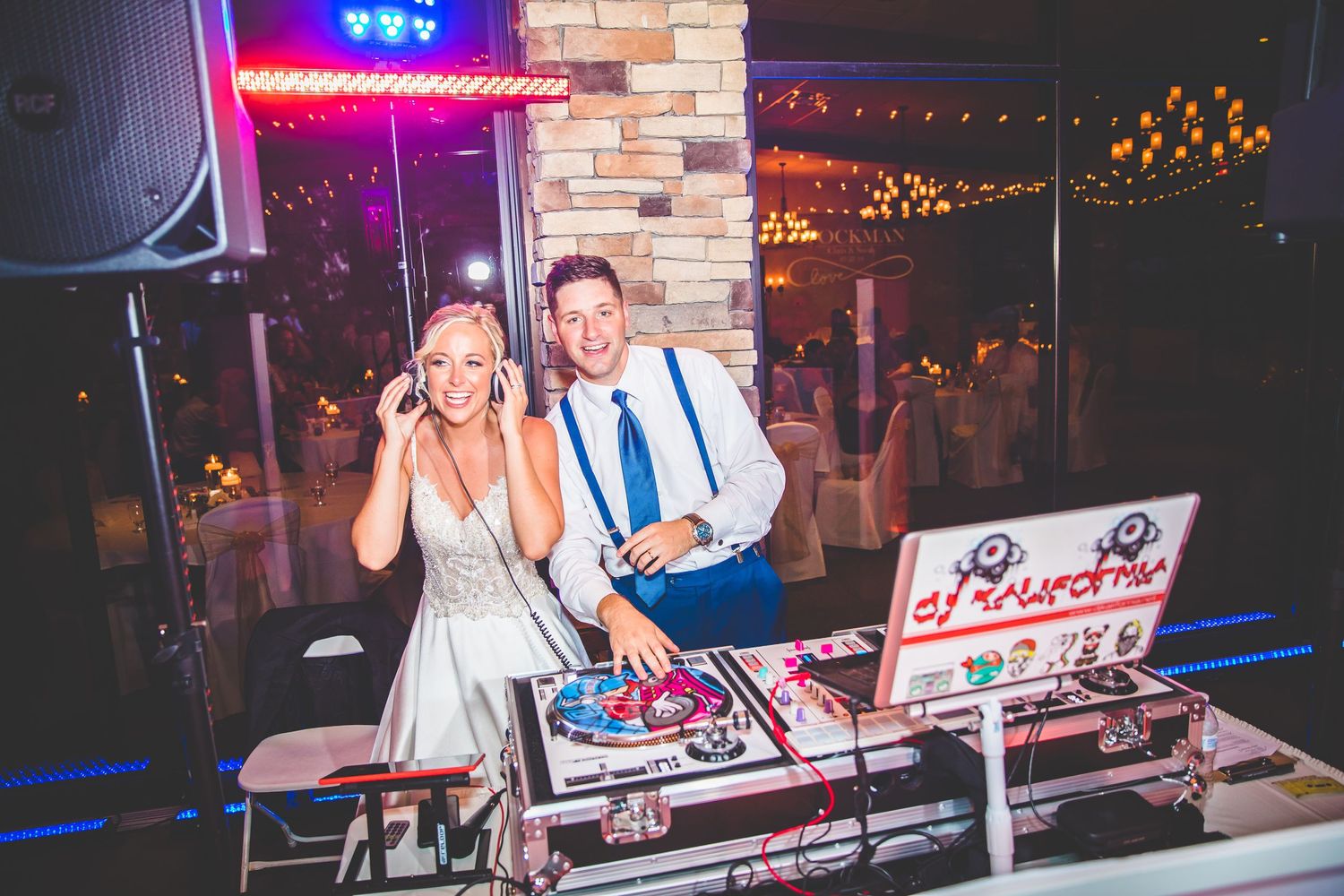 DJ booth setup with colorful lighting at a wedding reception.