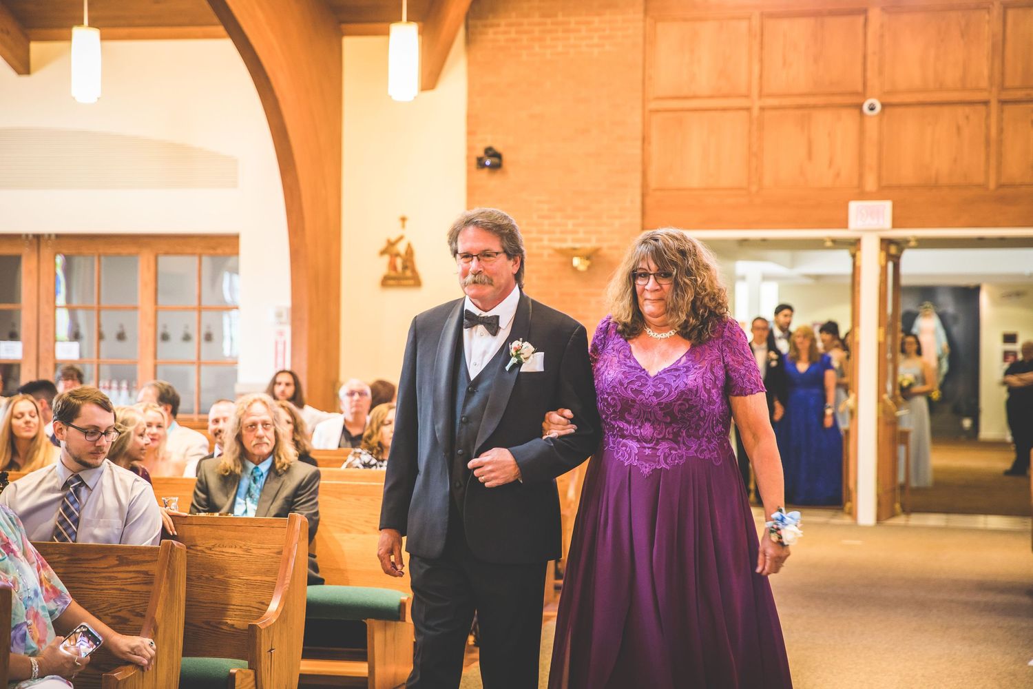 Wedding processional in a church with purple and blue formal attire.