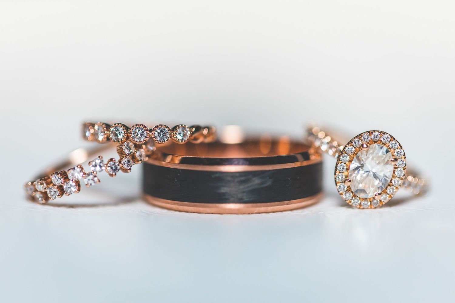 Close-up of rose gold wedding rings with diamond details on white surface.