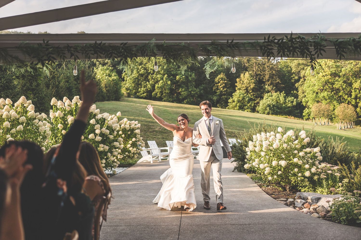 Scenic outdoor wedding venue with white tent and garden setting during golden hour.