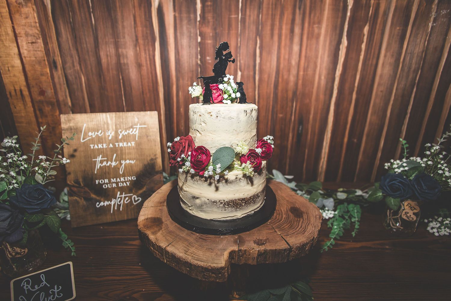 Rustic wooden wall backdrop with elegant wedding cake display and floral decorations.