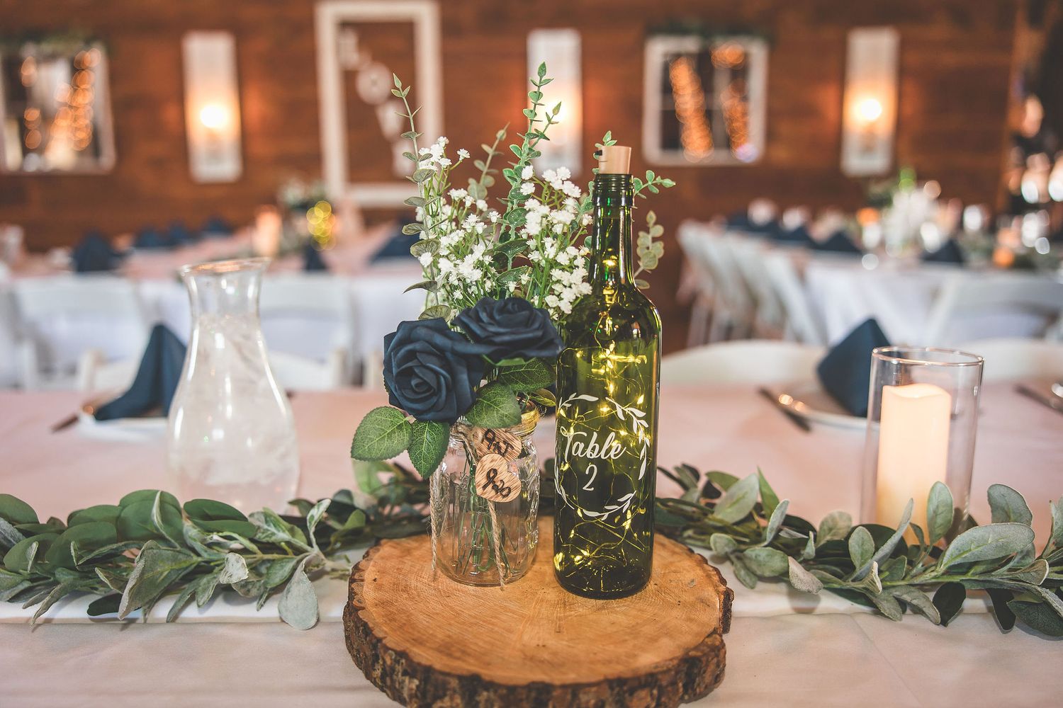 Elegant table settings with eucalyptus garlands and wooden accents at a rustic wedding reception.