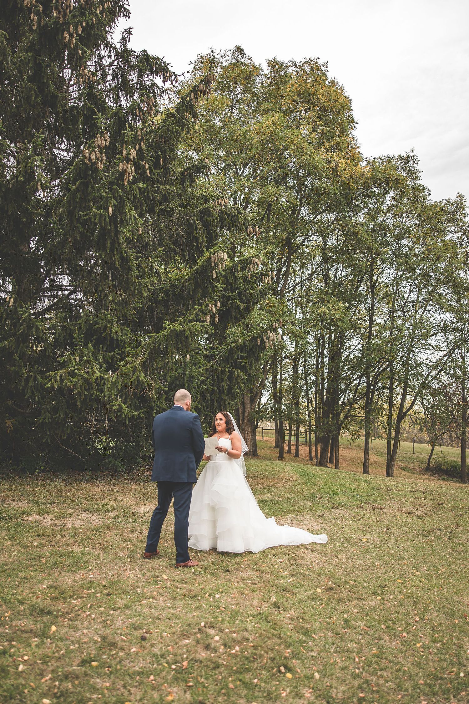 A couple stands together during their wedding ceremony in a serene wooded setting.