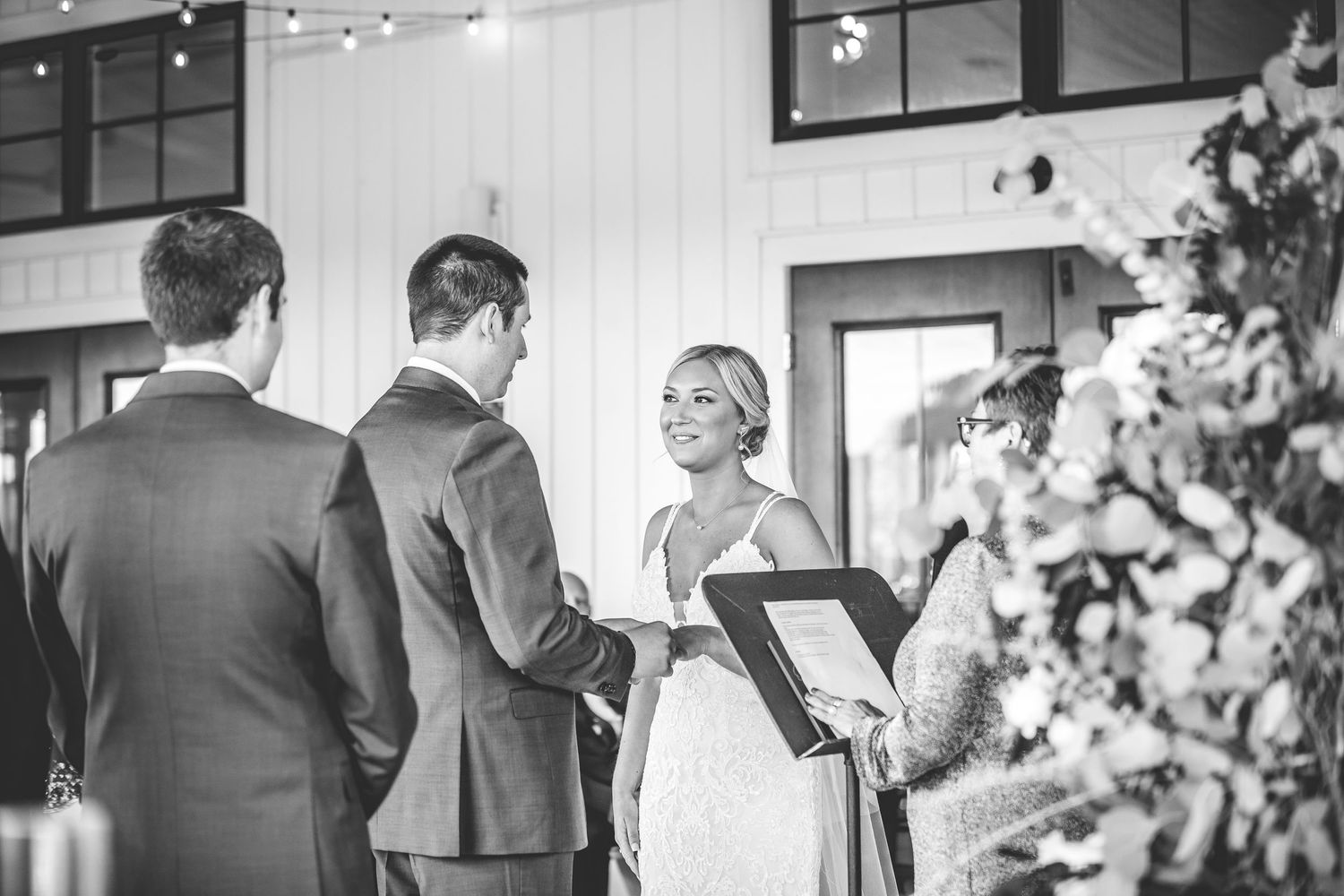 Black and white photo of a wedding ceremony in a modern indoor venue with elegant decor.
