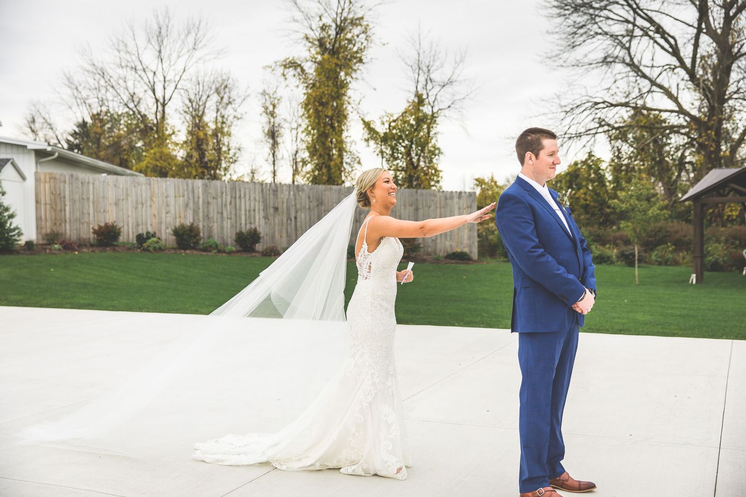 First look wedding photos taken on a lawn with autumn trees in background.