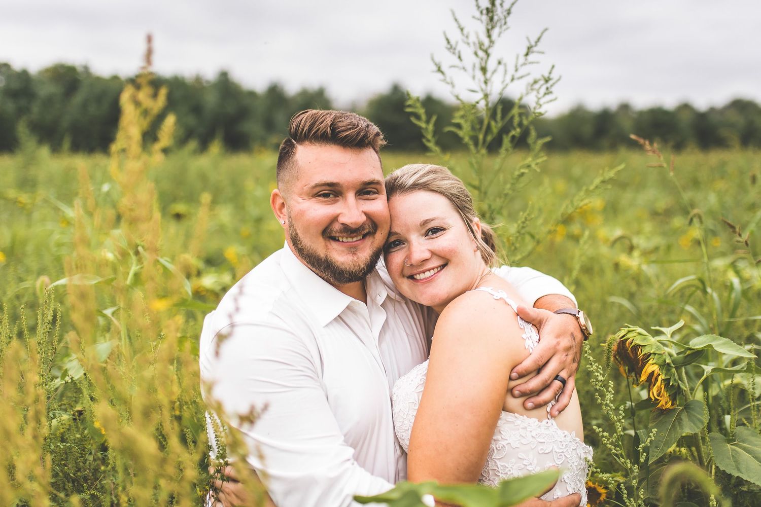 Couple sharing intimate moment among tall wildflowers in a field.