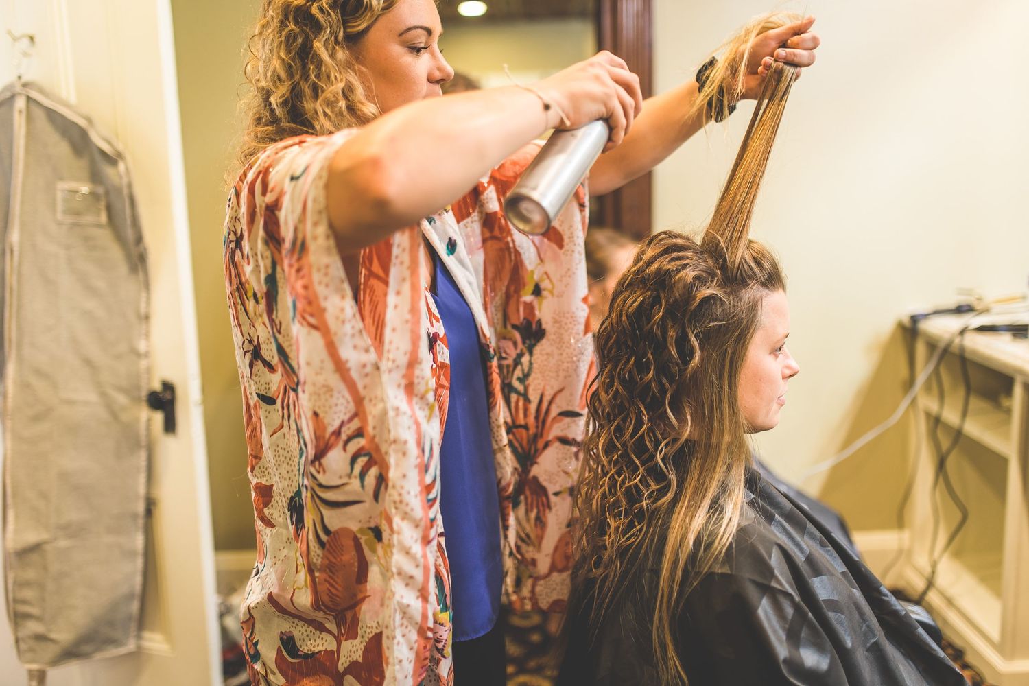 A stylist working on someone's hair in a salon preparation setting.
