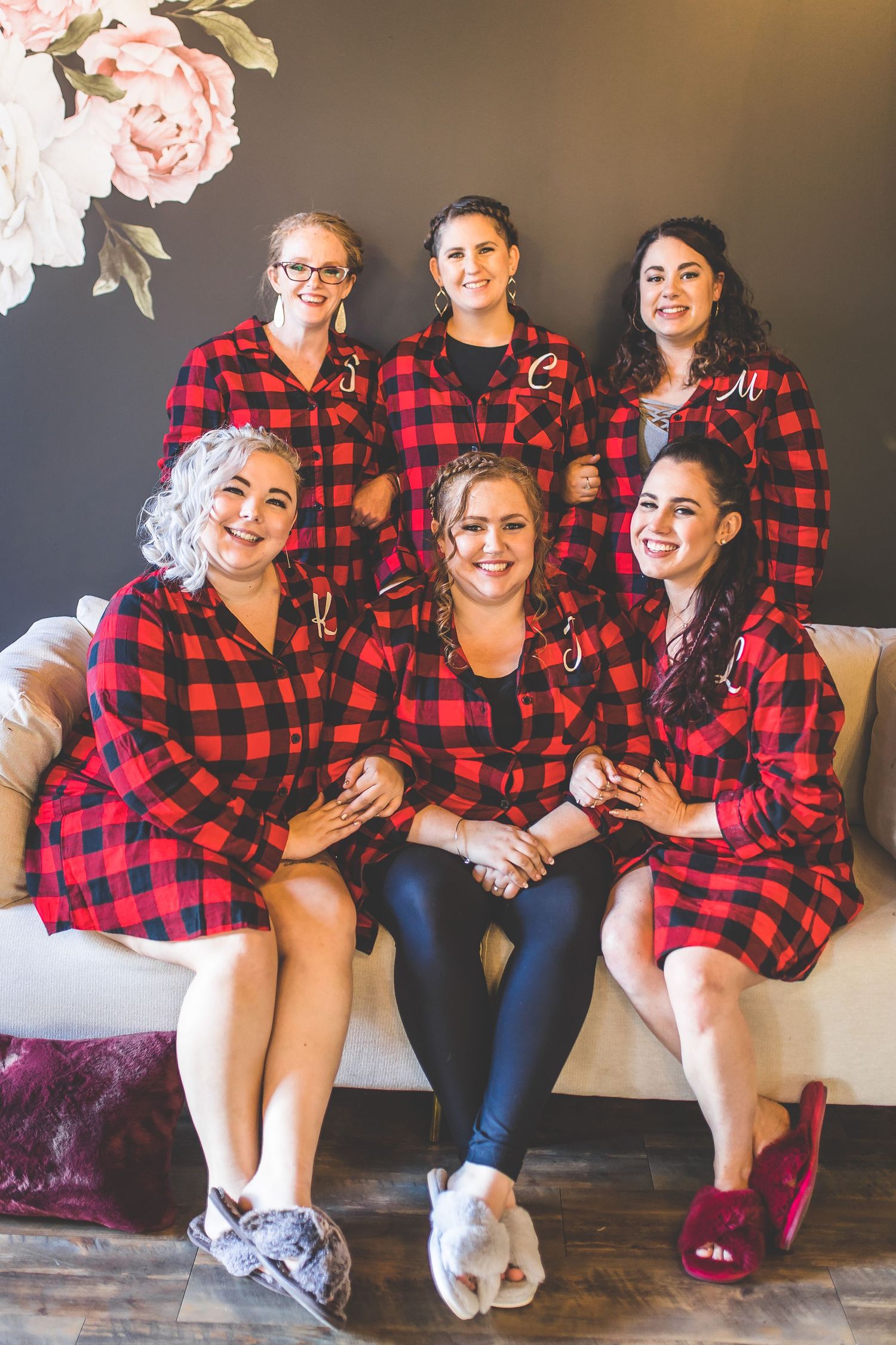 Group wearing matching red and black buffalo plaid shirts sitting together on couch.