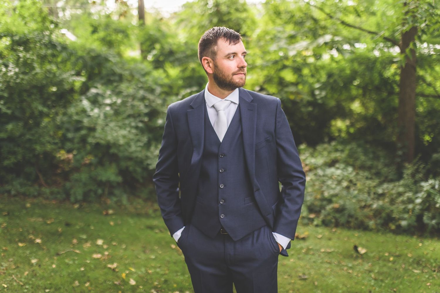 Groomsmen in navy three-piece suits posing in a garden setting.