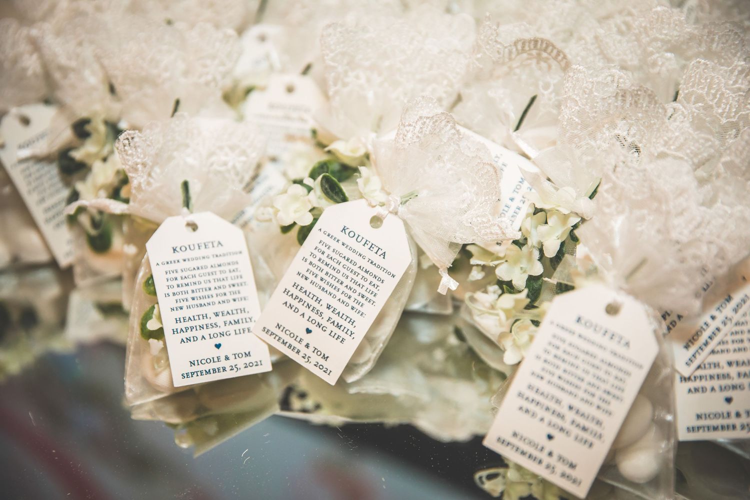 Wedding favor tags with handwritten messages arranged on lace fabric.