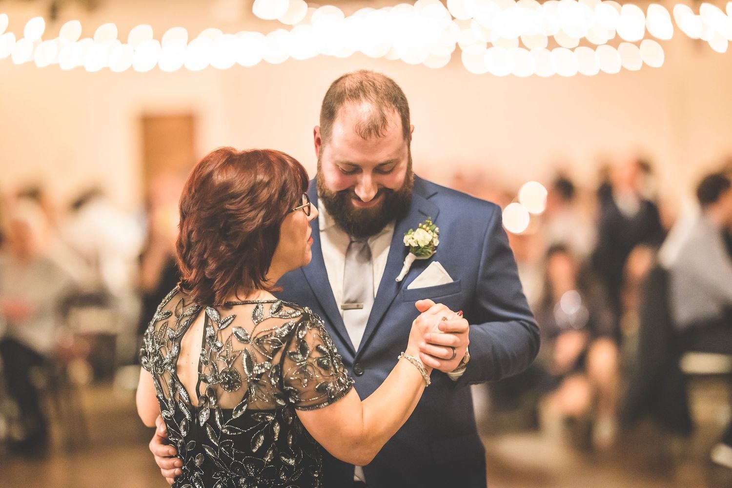 Wedding reception dance floor with string lights and couples dancing in warm ambient lighting.