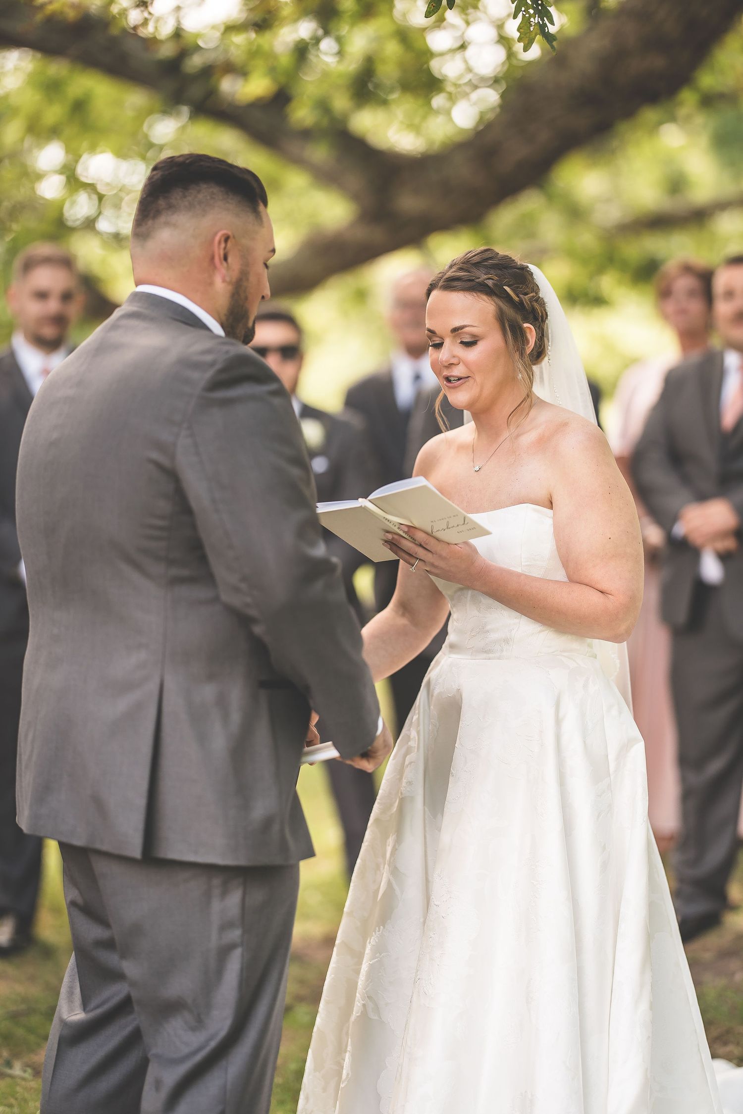 Candid moments captured during an outdoor wedding ceremony as couple reads their vows.