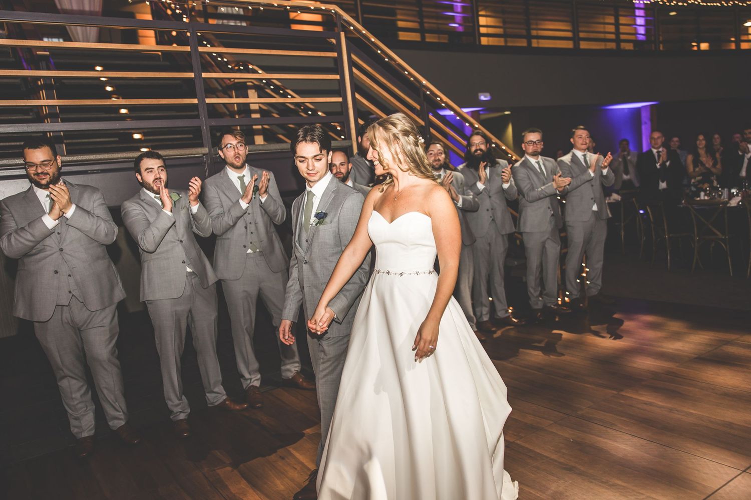 Wedding party in grey suits and white dress gathered for celebration.