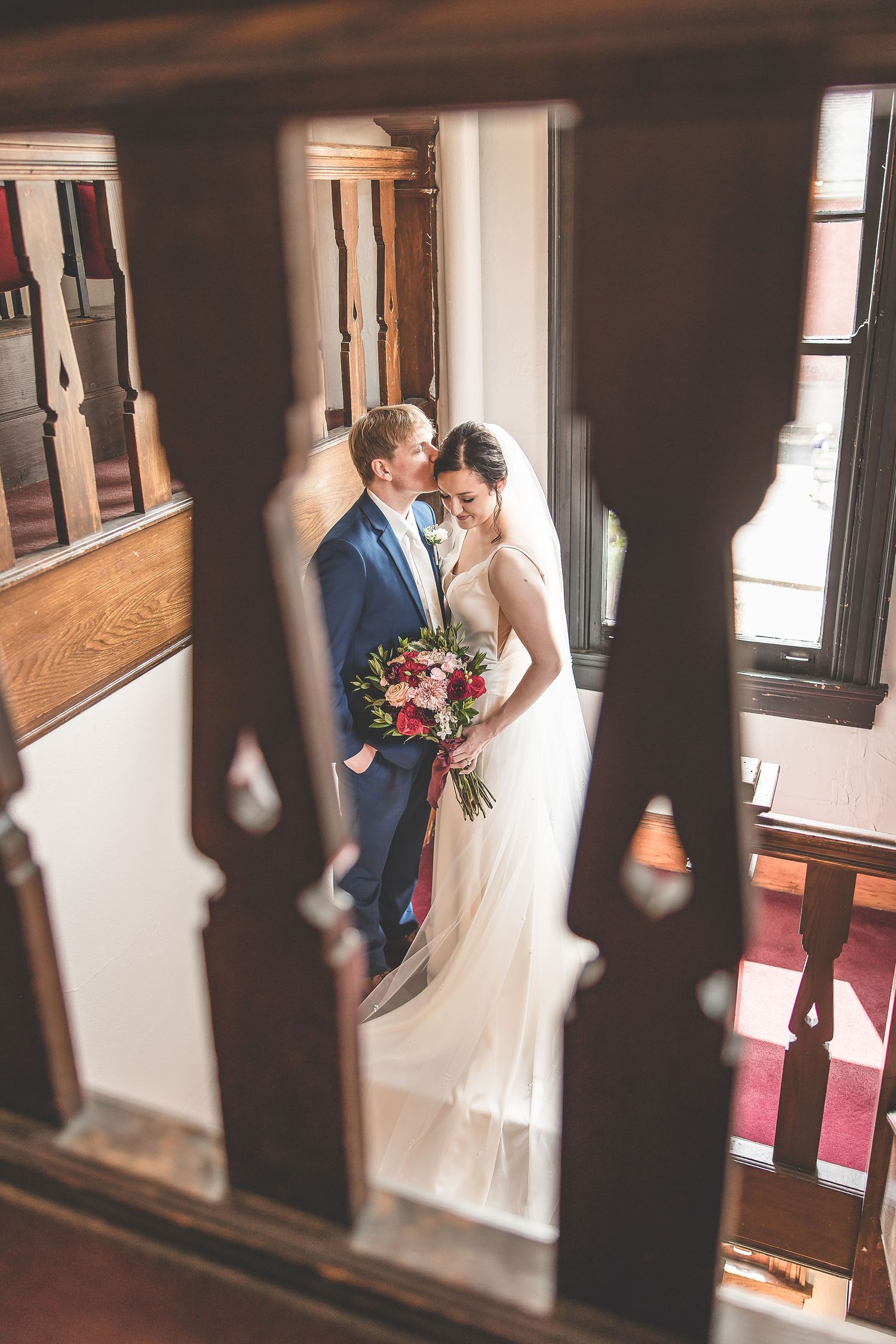 Artistic wedding photography through theater railings captures an intimate moment in vintage setting.