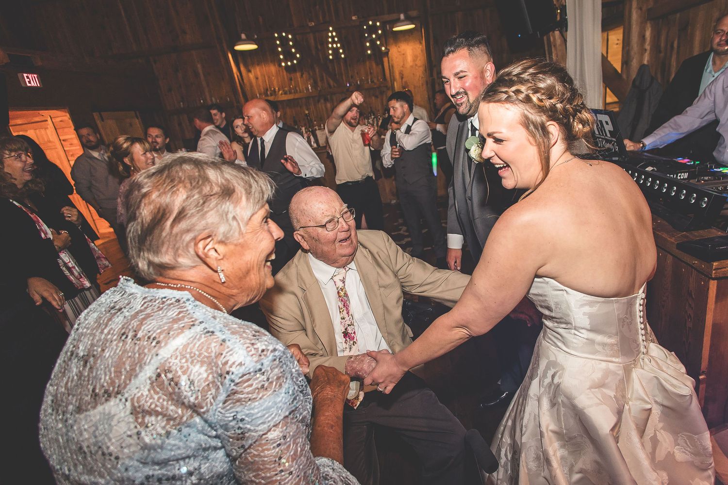 Wedding guests dancing and celebrating during an evening reception in a rustic barn setting.