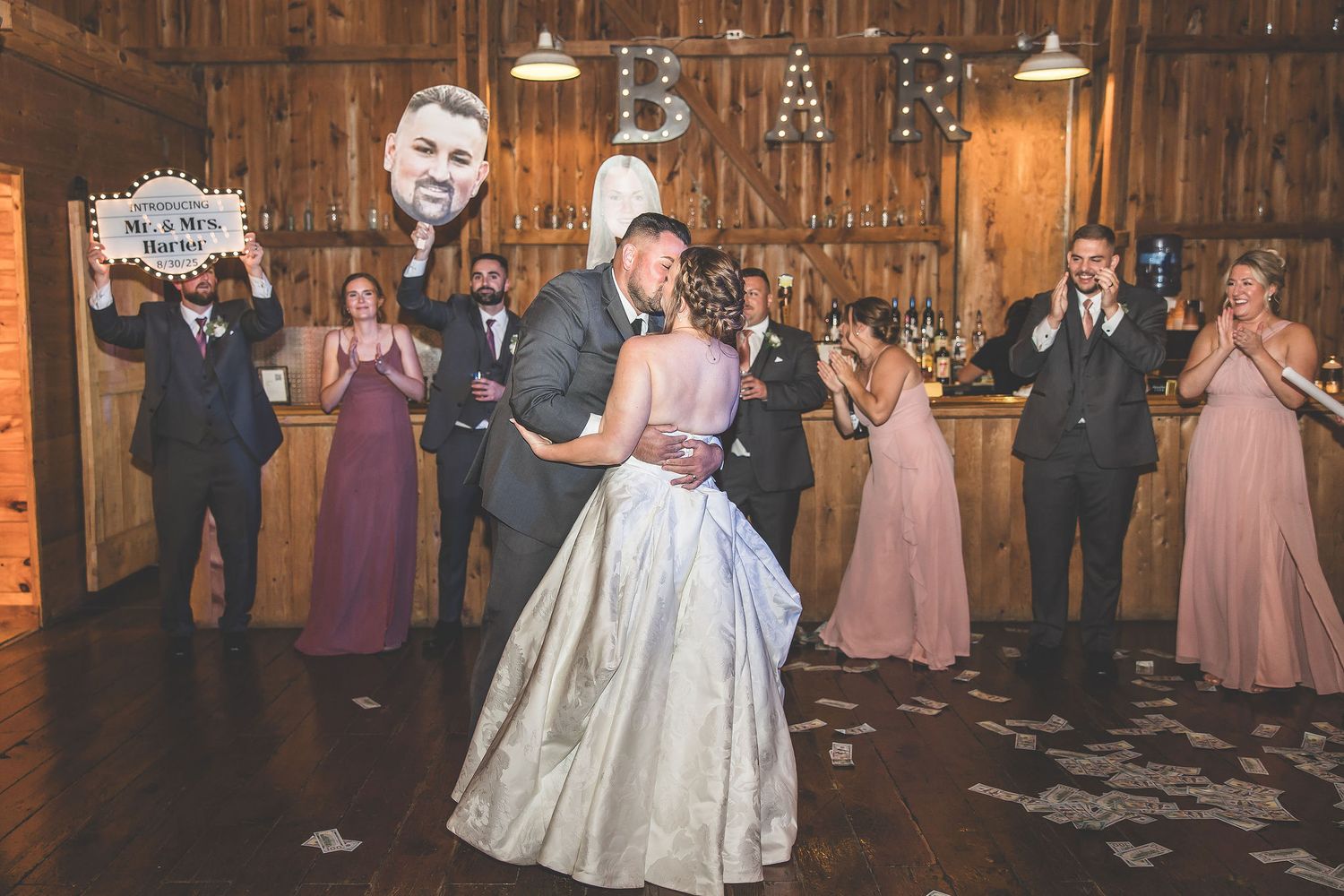 Wedding party dancing and celebrating in rustic barn venue with pink bridesmaid dresses.