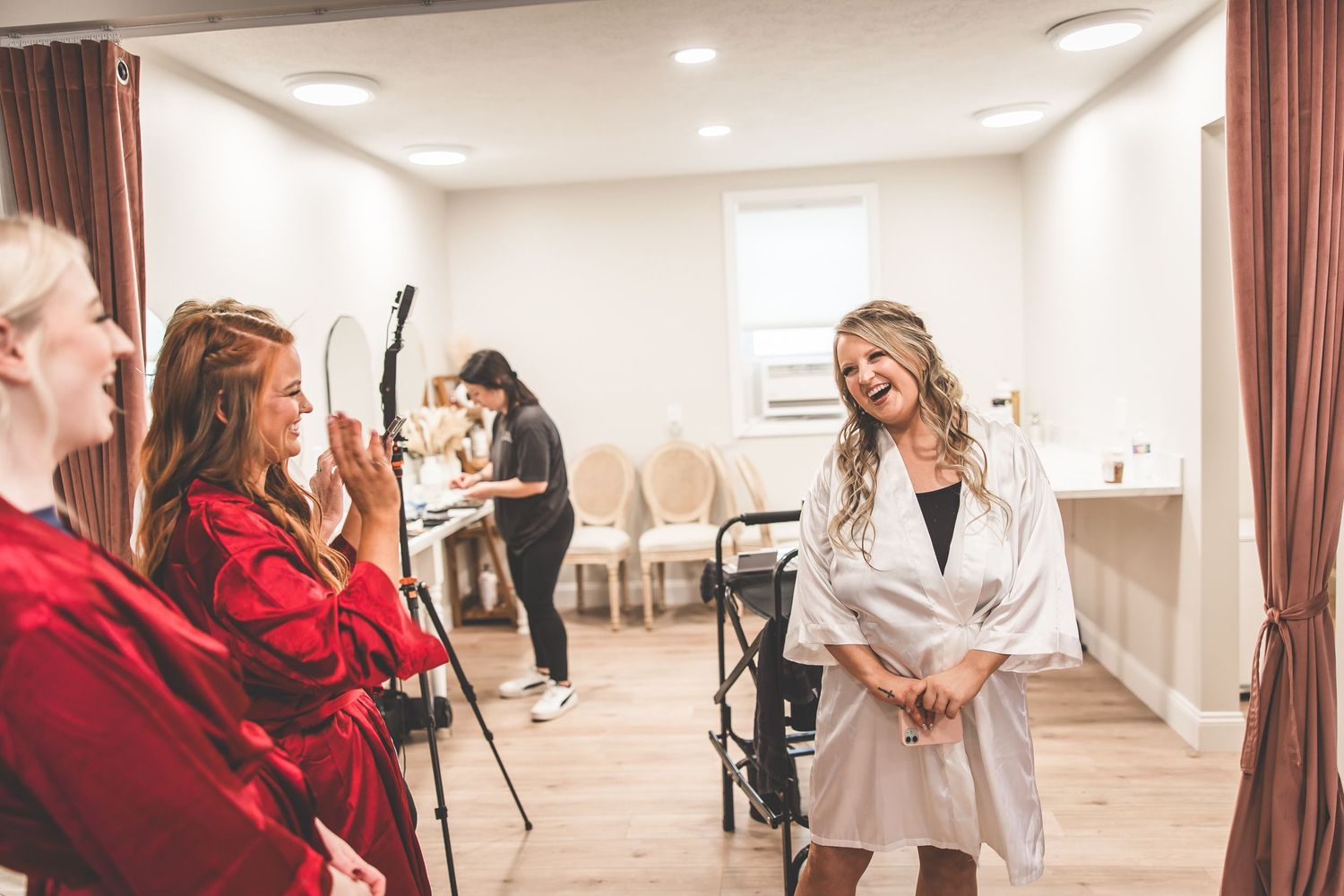 Wedding preparation scene in a bright indoor room with people in robes.