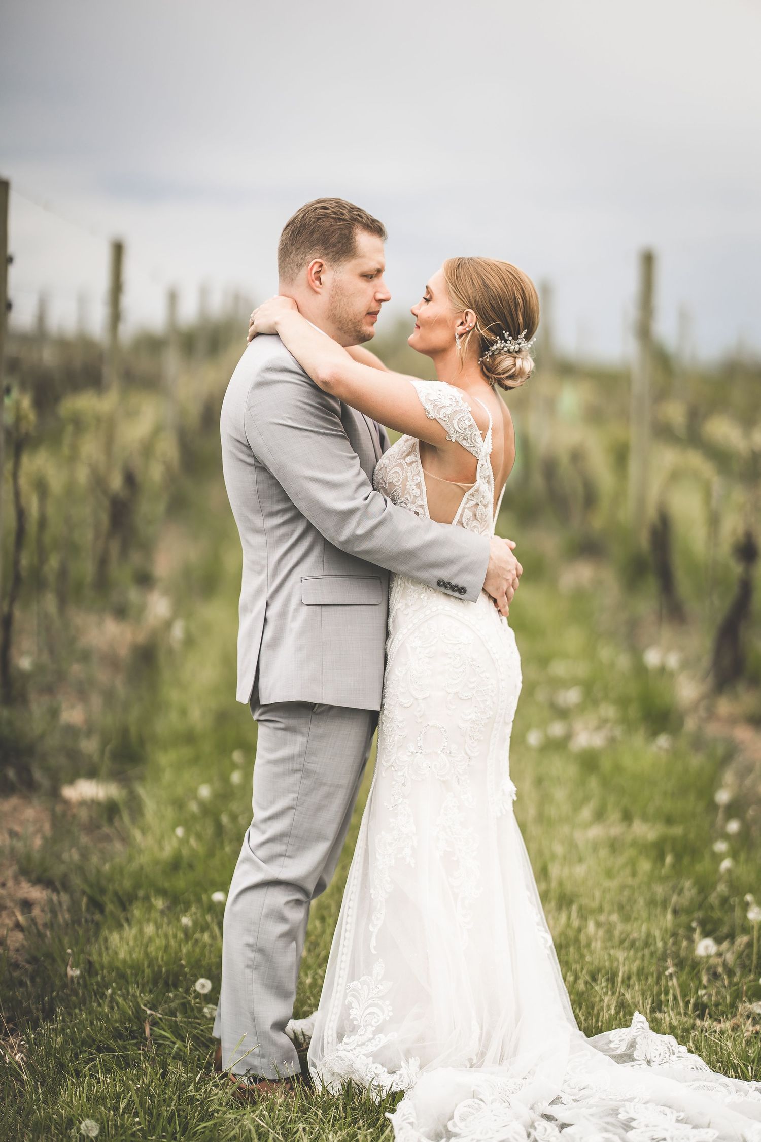 A romantic wedding photo of a couple embracing in a desert garden with tall cacti in the background.