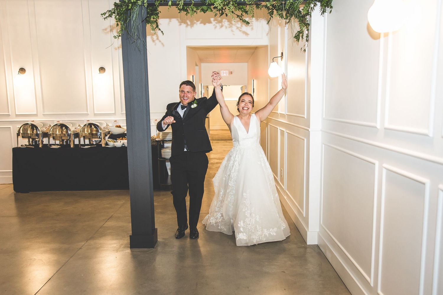 Wedding venue decorated with greenery garlands and modern white paneled walls.