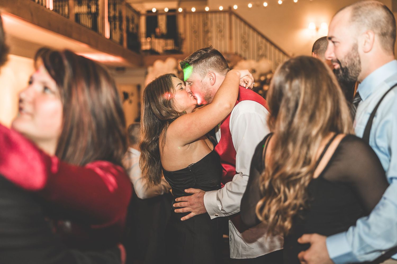 Party guests dancing under string lights at an indoor celebration.