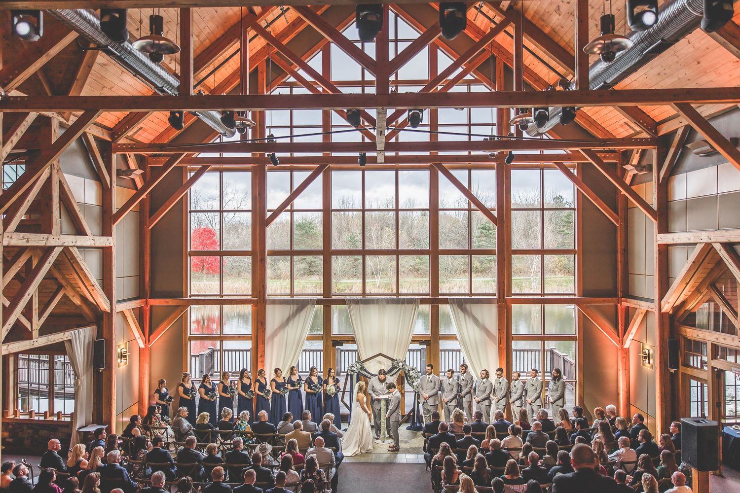 Wedding ceremony in rustic wooden beam venue filled with guests.