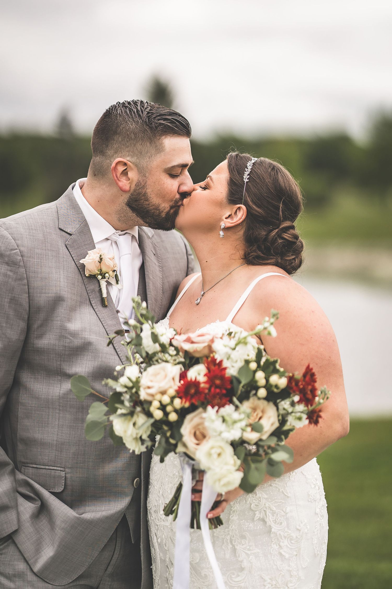 Newlyweds share an intimate moment with bouquet during outdoor wedding photo session.