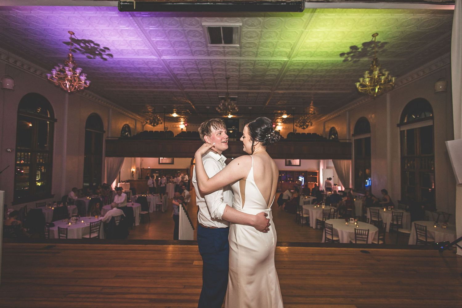 Wedding reception dance floor with purple and yellow mood lighting illuminating the celebration.