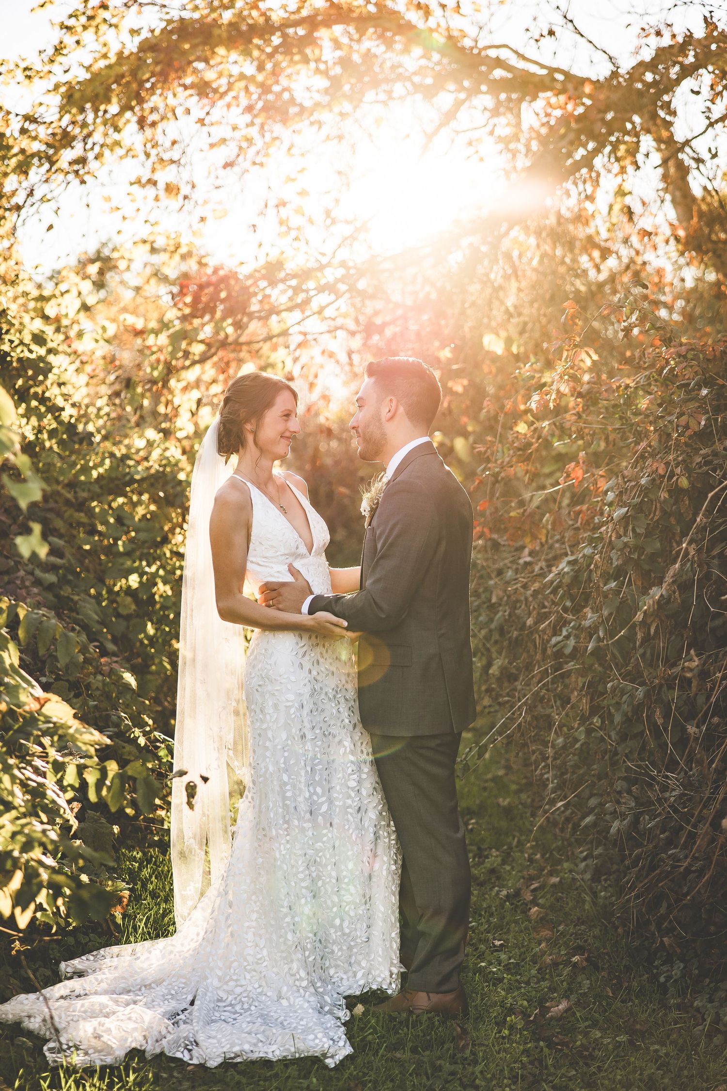 Romantic wedding portrait in golden sunset light through autumn foliage.