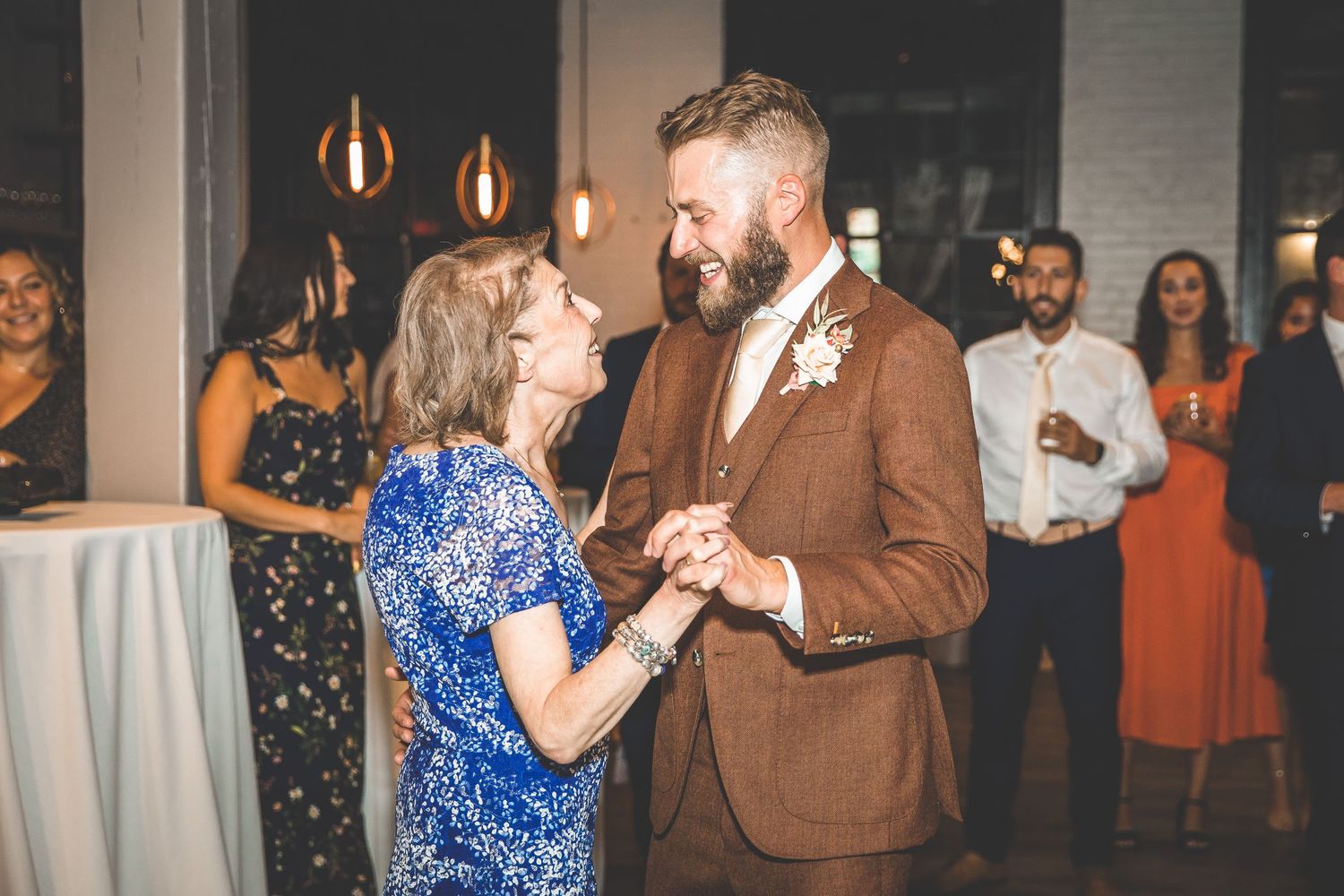 A couple shares a dance moment in formal attire at an indoor reception.