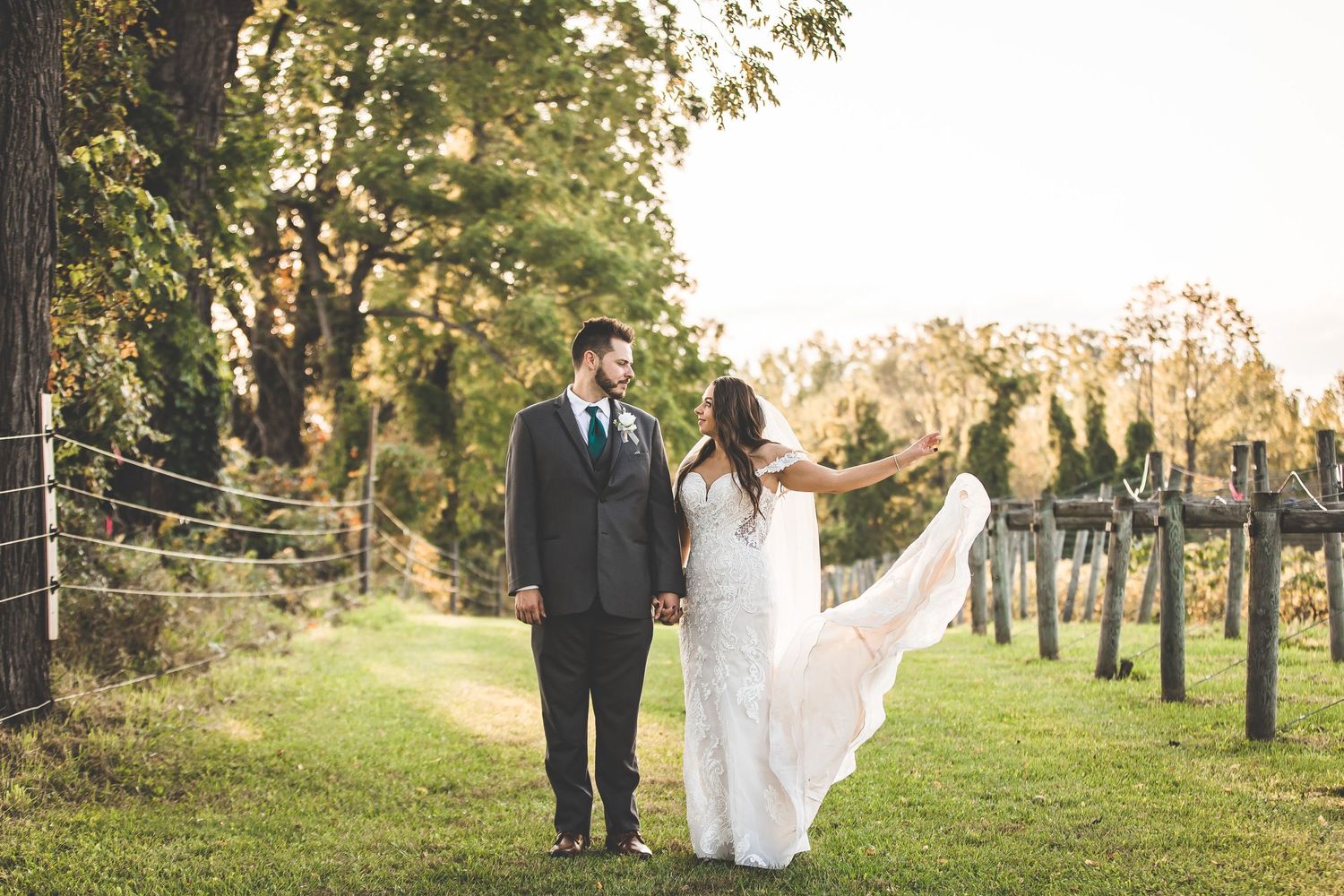 Newlyweds walking together on a tree-lined path during their wedding day.