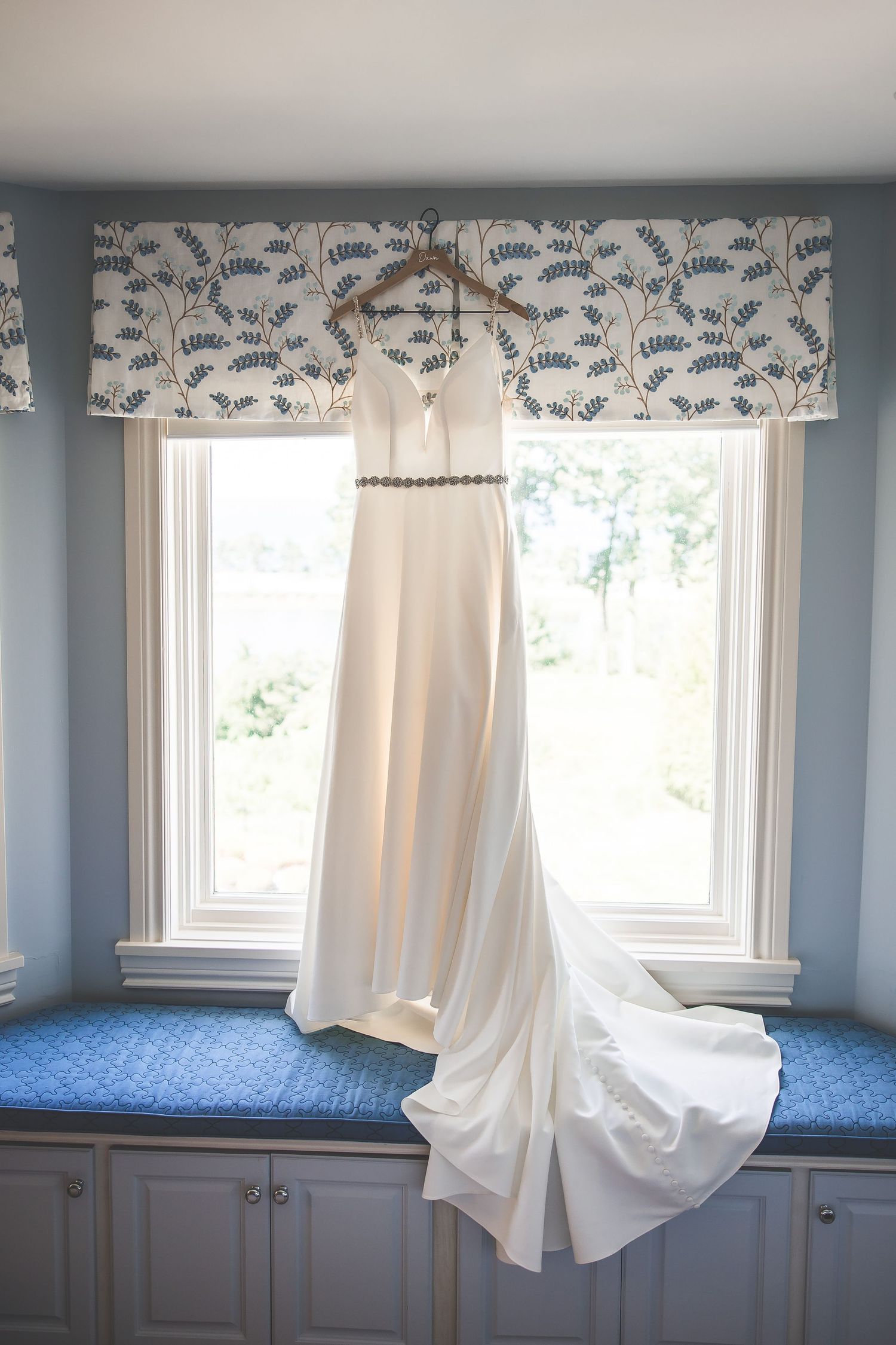 Blue room with window seats and white curtains featuring floral pattern valances.
