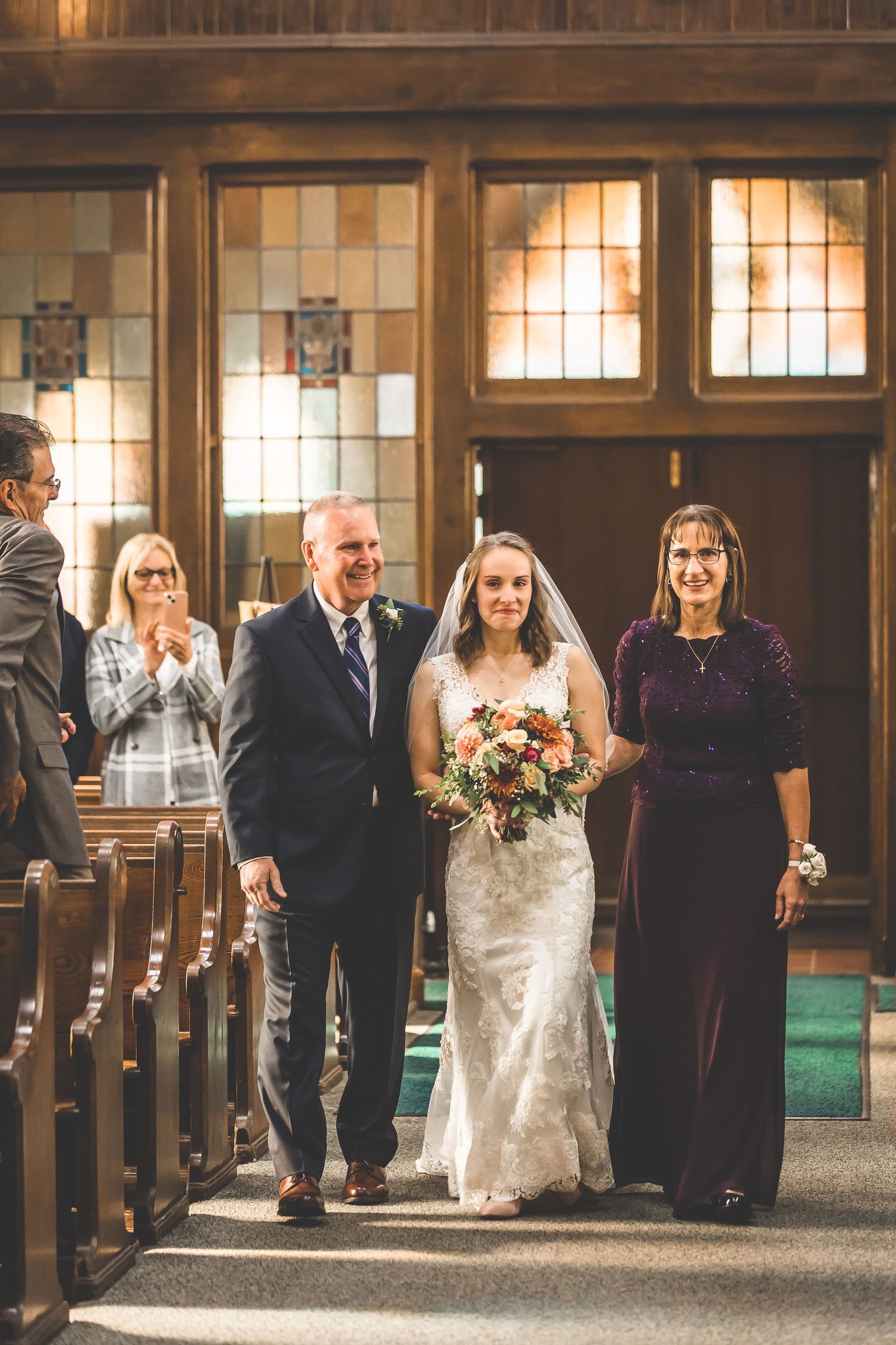 Wedding party walking down the aisle in a traditional church with wooden pews.