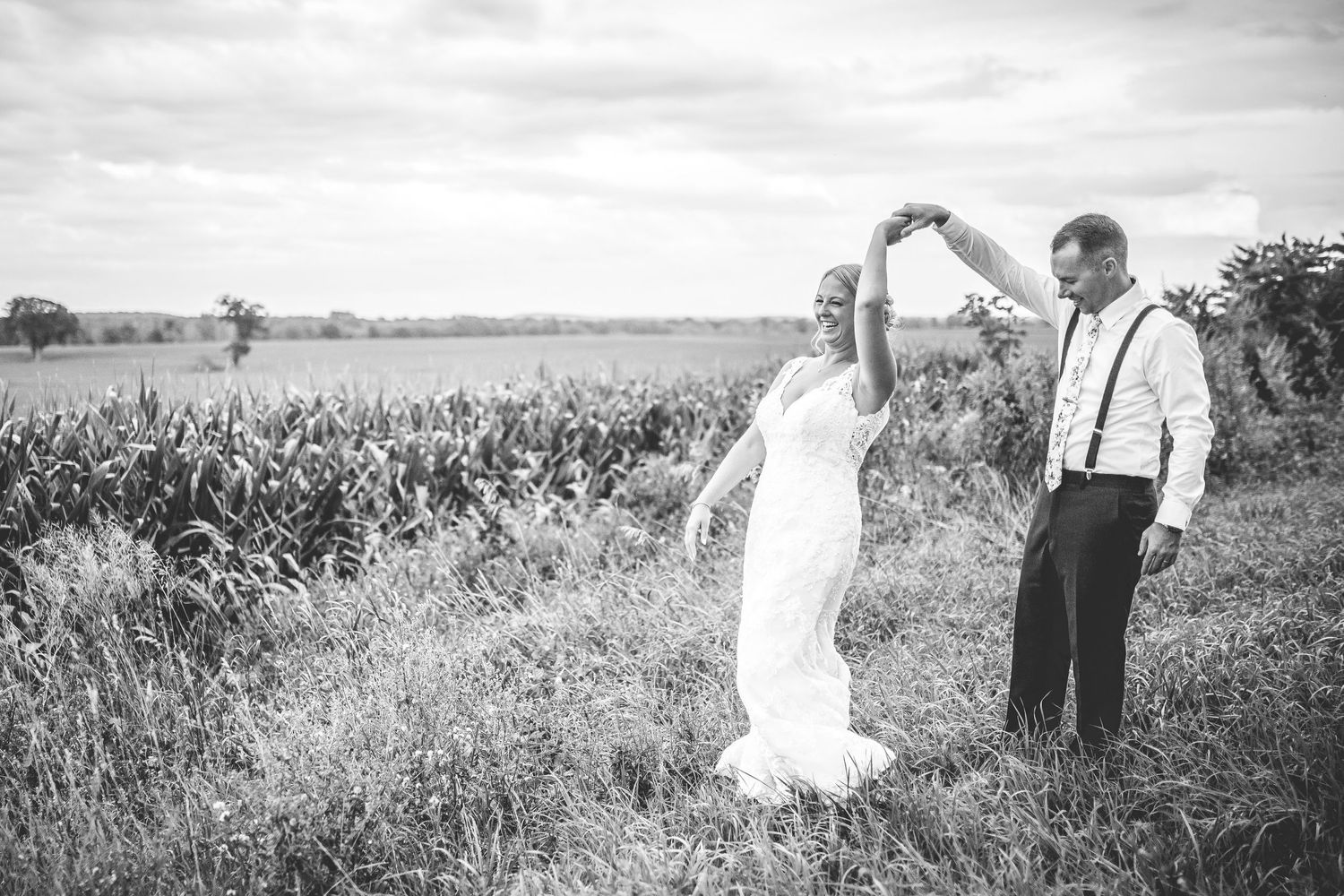 Black and white wedding photography showing couple in a rural field setting.