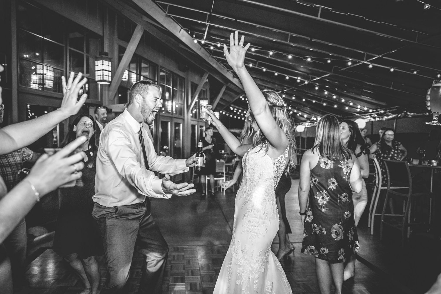 Wedding reception dance party with guests celebrating under string lights.