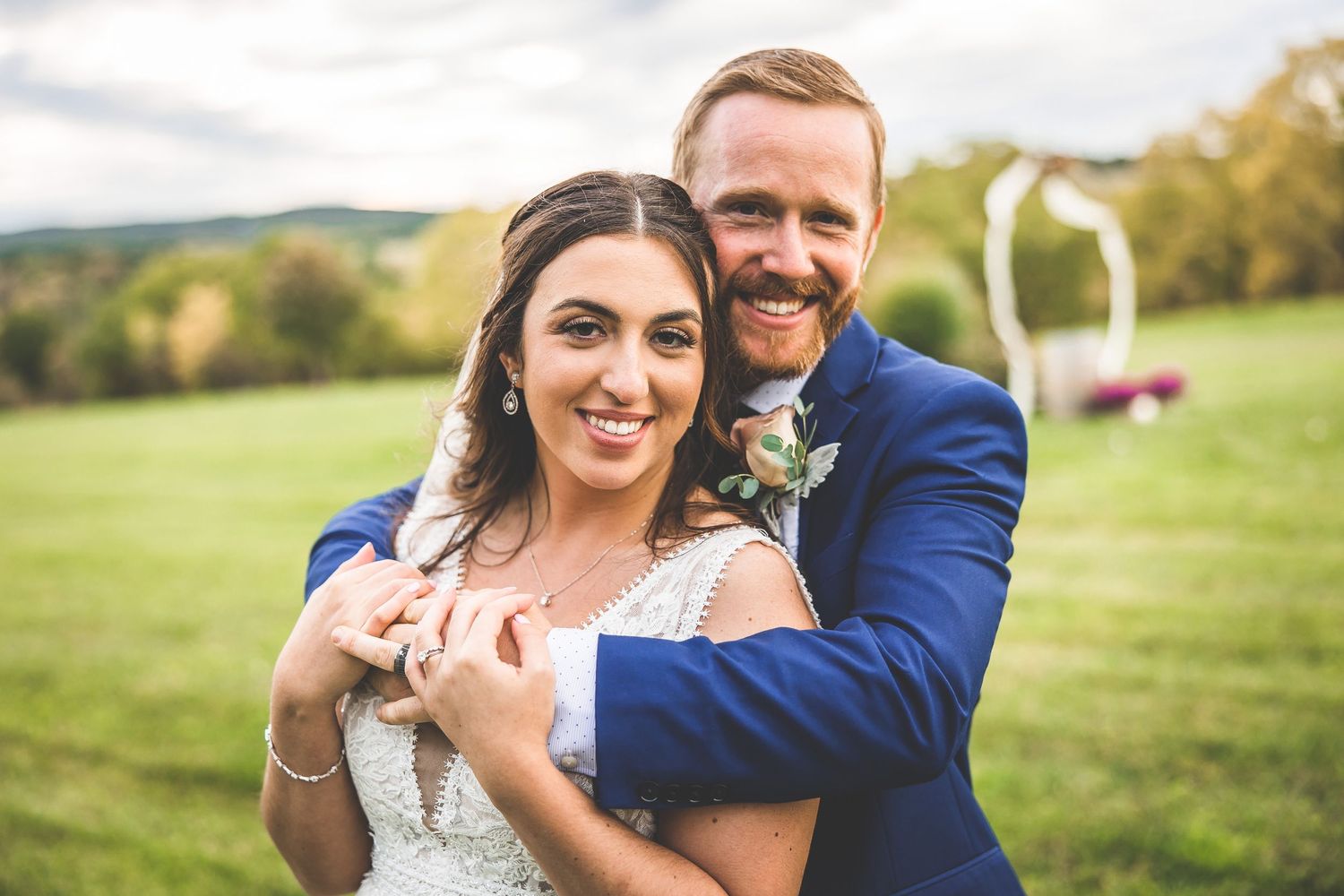 Newlyweds share tender moments during their outdoor wedding photoshoot in a grassy field.