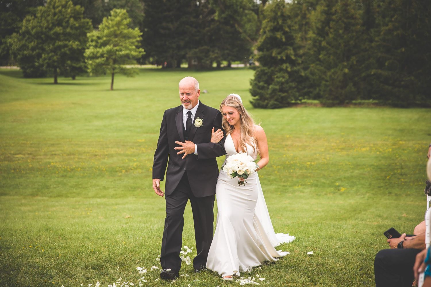 Outdoor wedding ceremony on a lush green lawn with guests seated.