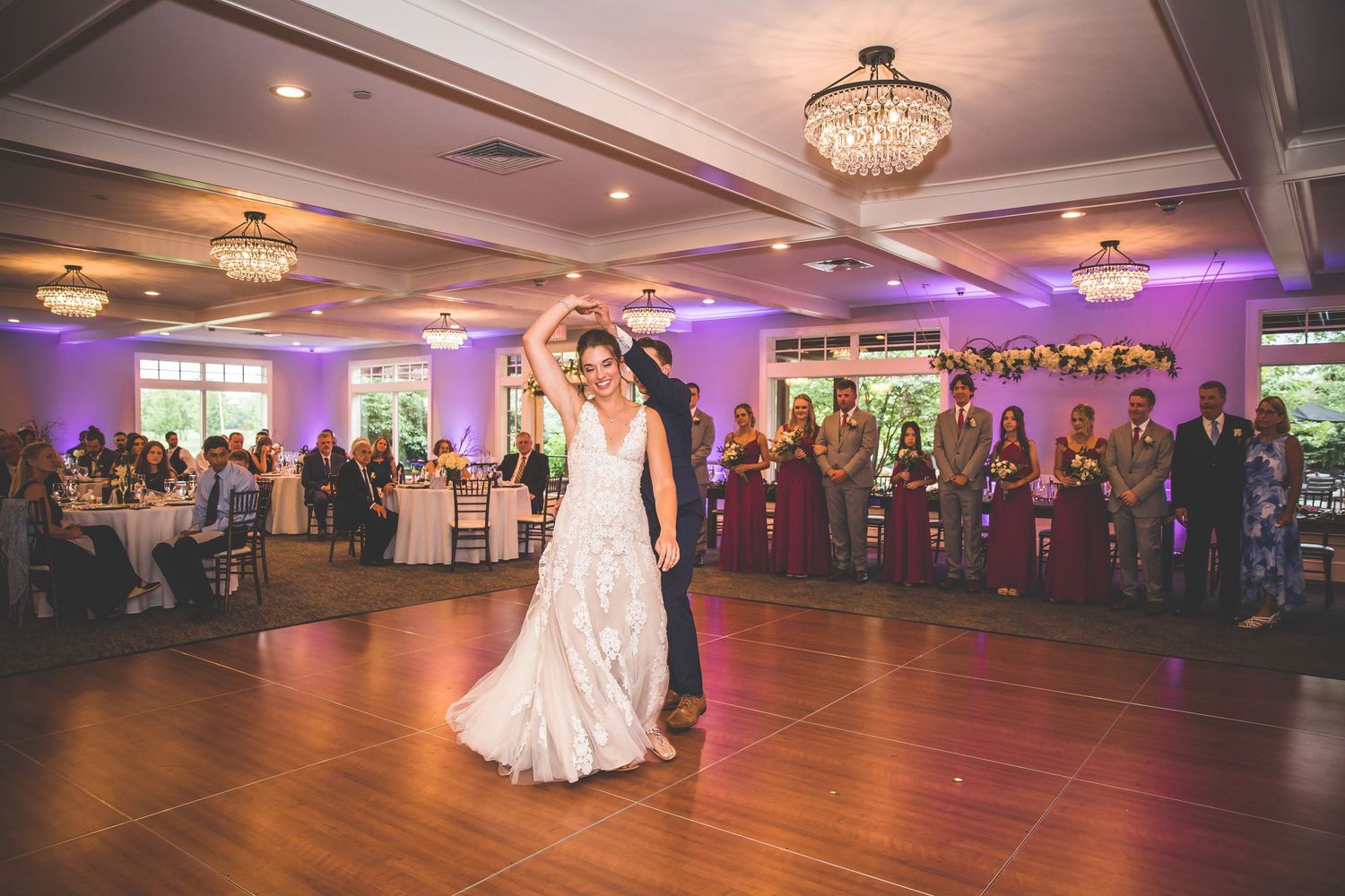 Wide angle view of a wedding reception venue with elegant lighting and couples dancing on the dance floor.
