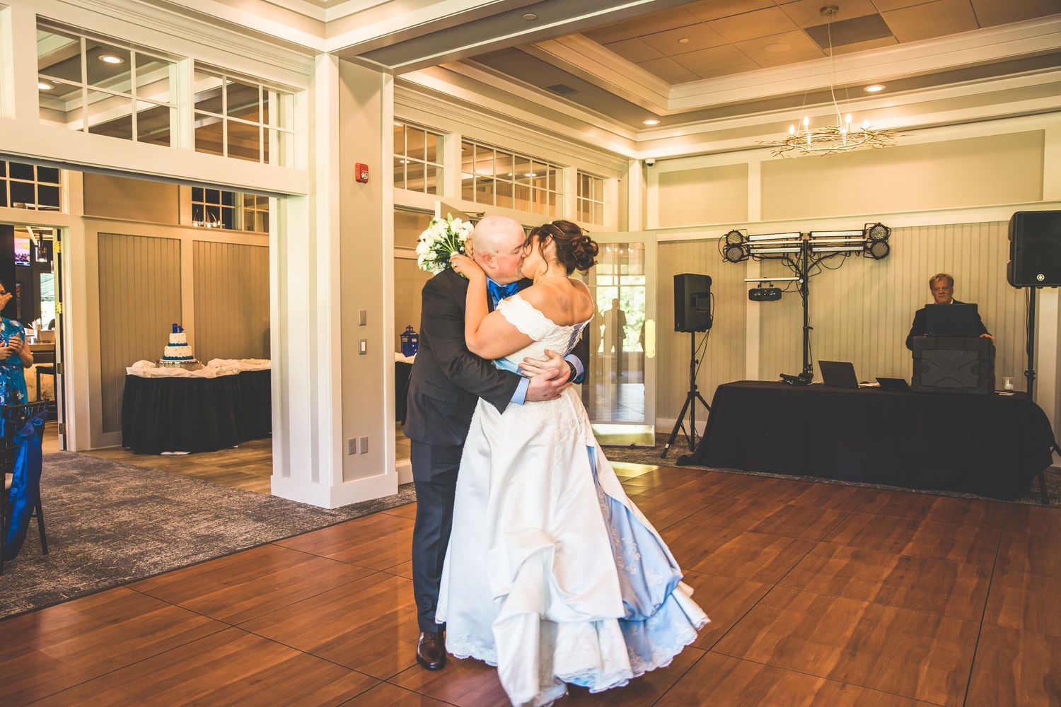 Wedding couple dancing in elegant ballroom with hardwood floors and white trim.