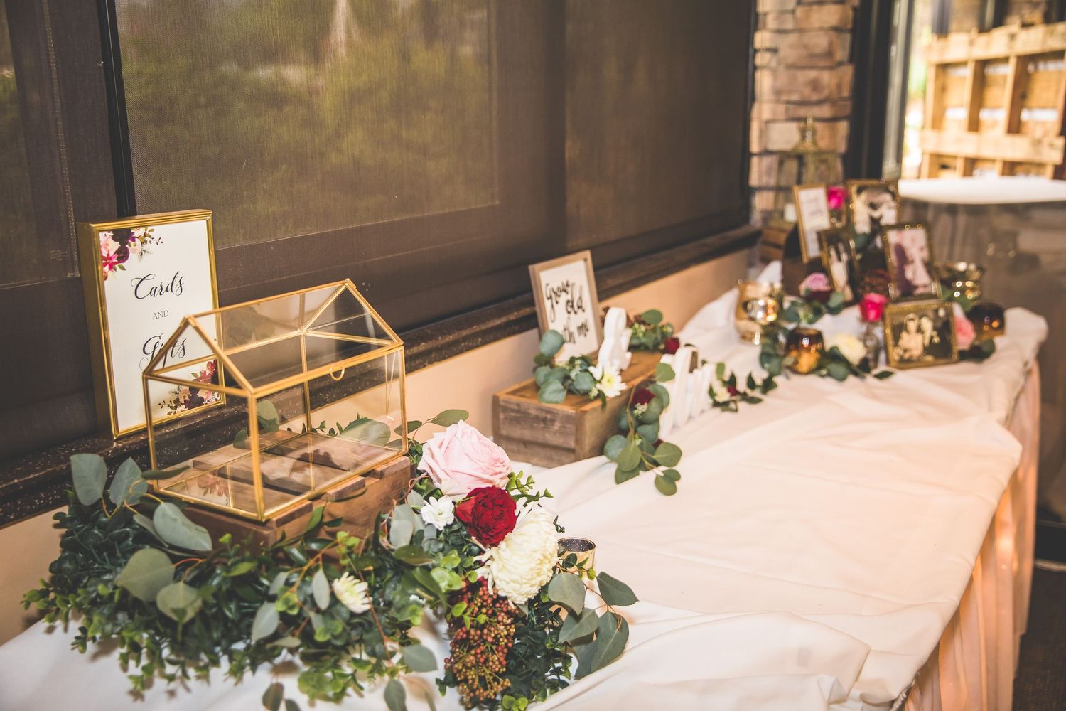 Wedding gift table decorated with floral arrangements, candles and rustic decor elements.