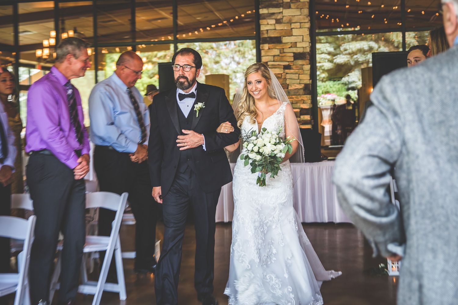 Wedding ceremony in progress at an indoor venue with stone walls and string lights.