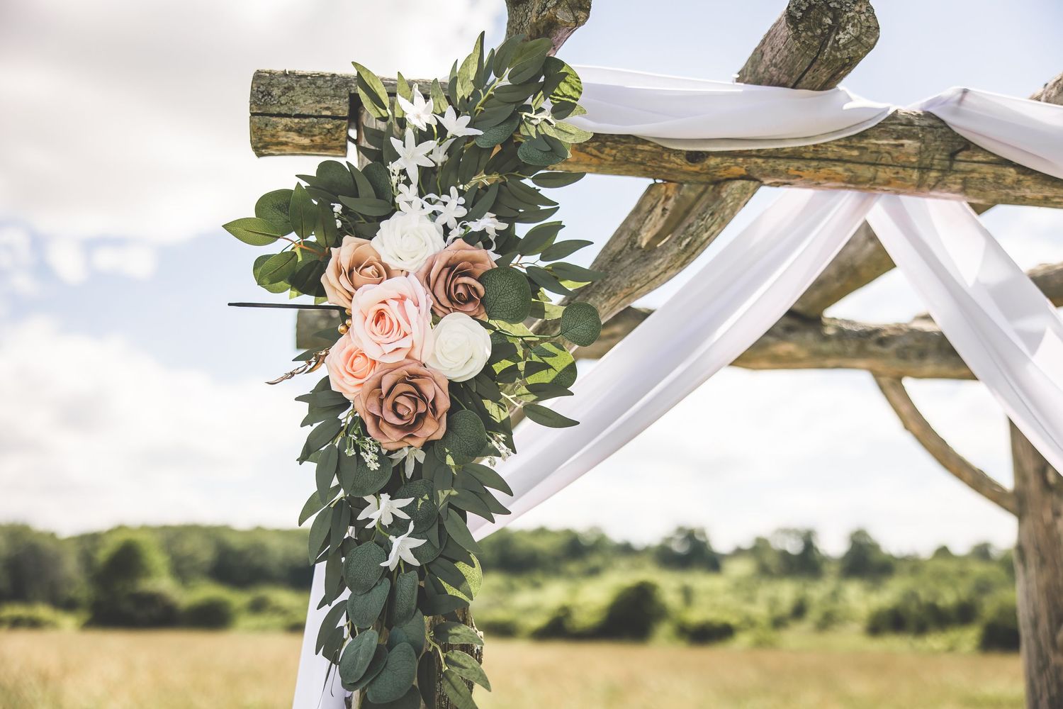 Wedding arch details showing delicate pink floral arrangements against white fabric.