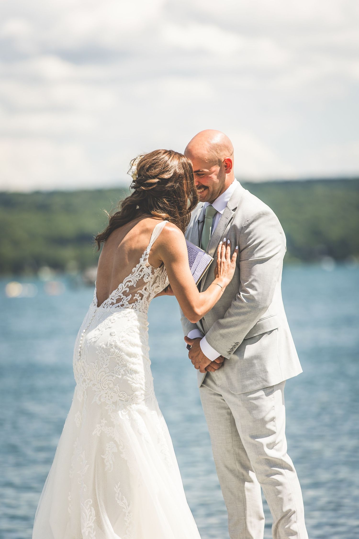 A tender moment between newlyweds captured against a stunning lakefront setting.