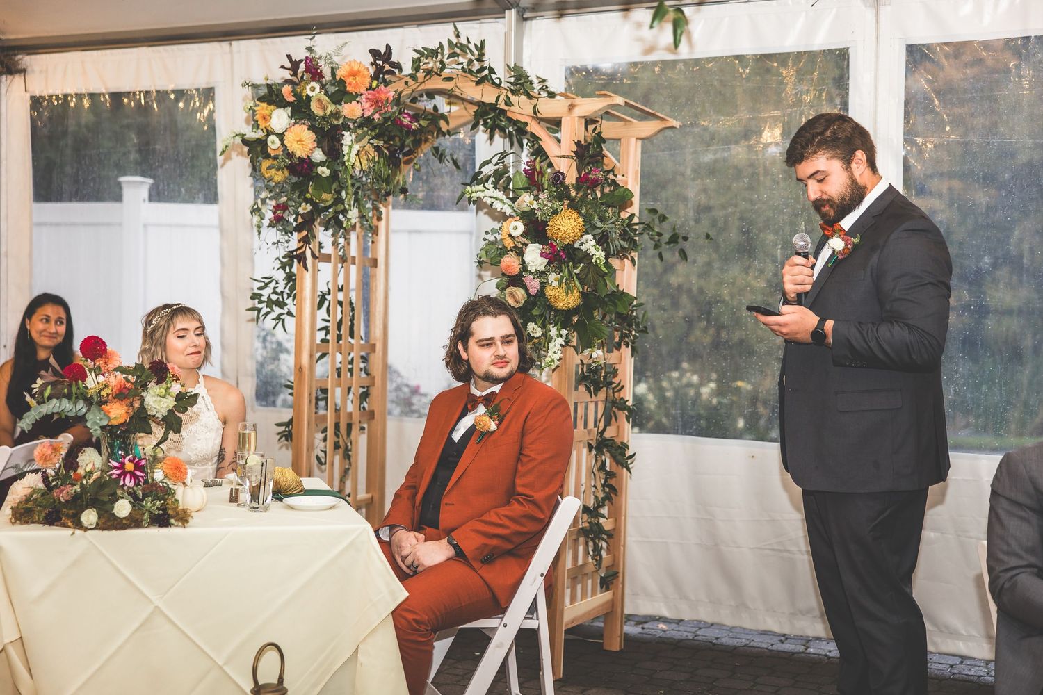 Wedding celebration in a tent venue with string lights and floral decorations.