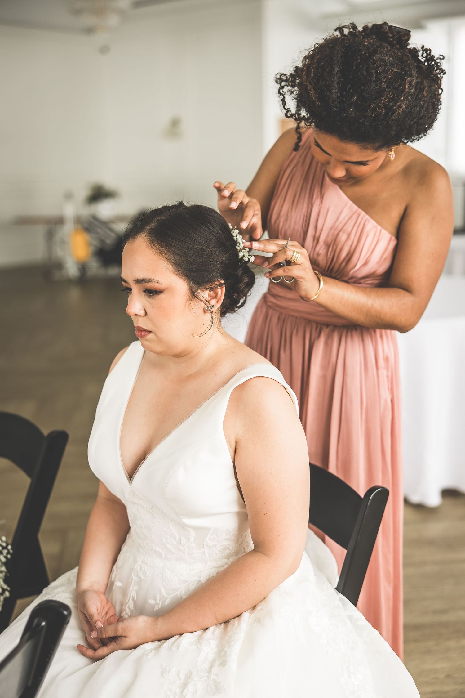 Final adjustments being made to wedding dress in bright indoor space.