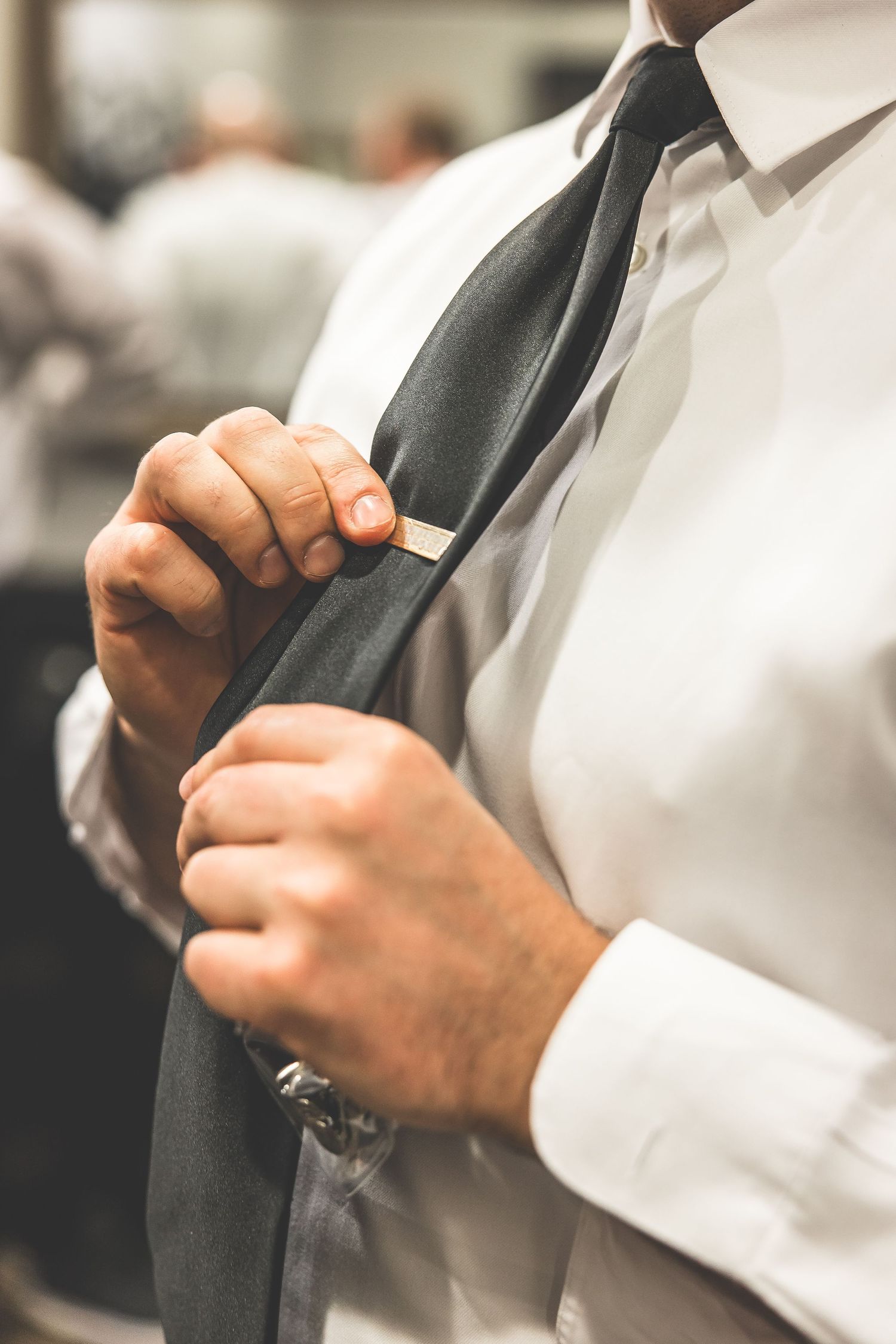 Close-up details of hands adjusting formal black ties and white dress shirts.