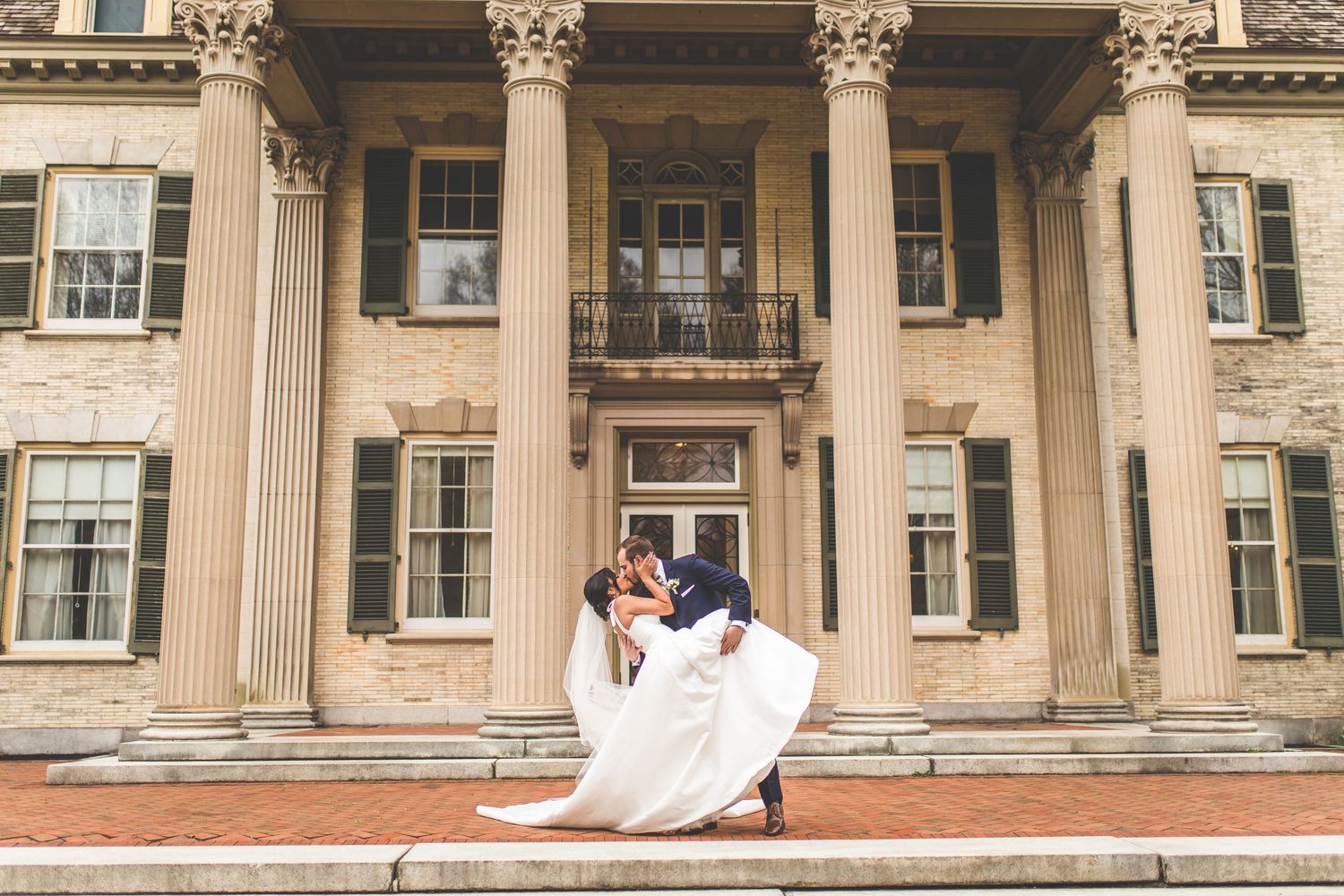 Classic engagement session in front of historic stone building with grand columns.