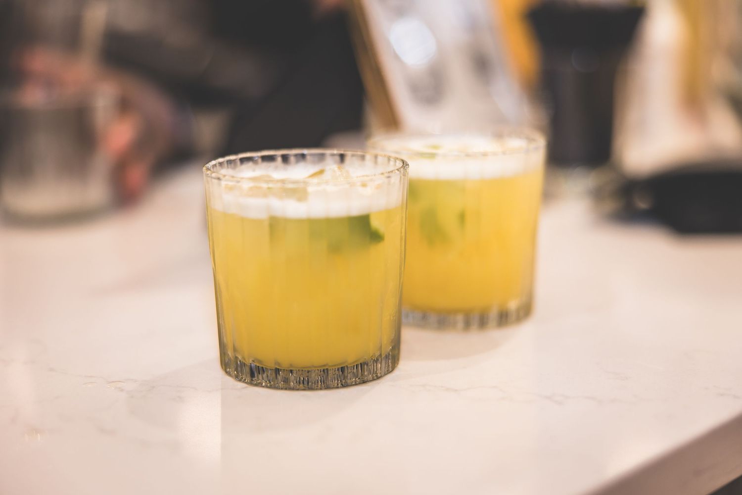 Close-up of yellow cocktails served in elegant glassware at an event.