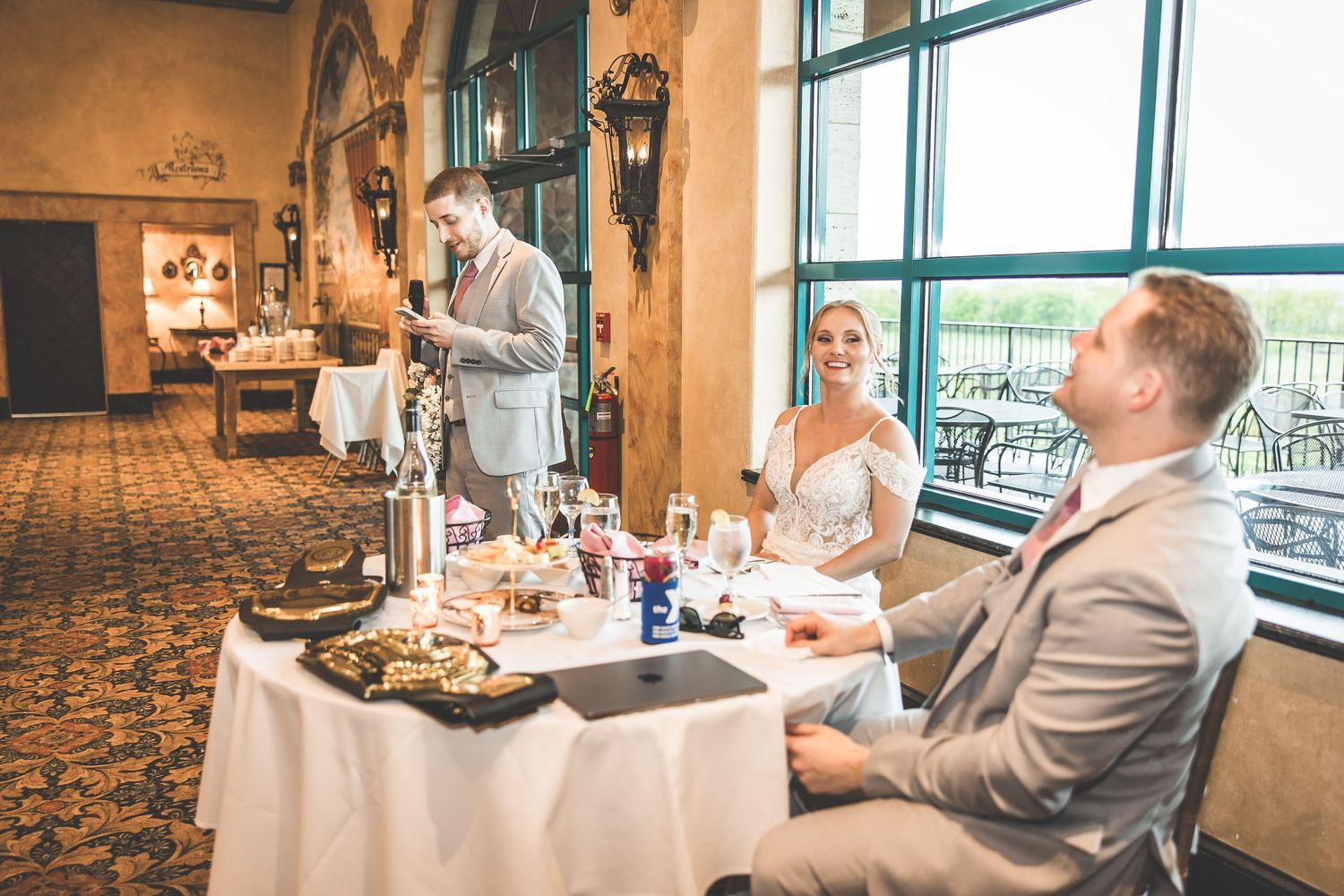 Couple enjoying a private moment during their wedding reception near large windows.